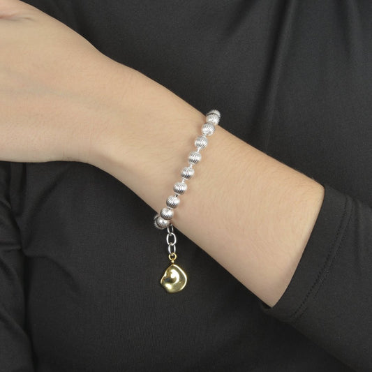 Ασημένιο βραχιόλι με ραβδωτές χάντρες και χρυσό στοιχείο στο κούμπωμα.