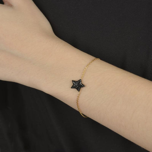 Χρυσό βραχιόλι με διακριτική αλυσίδα και μαύρο αστέρι διακοσμημένο με πέτρες.