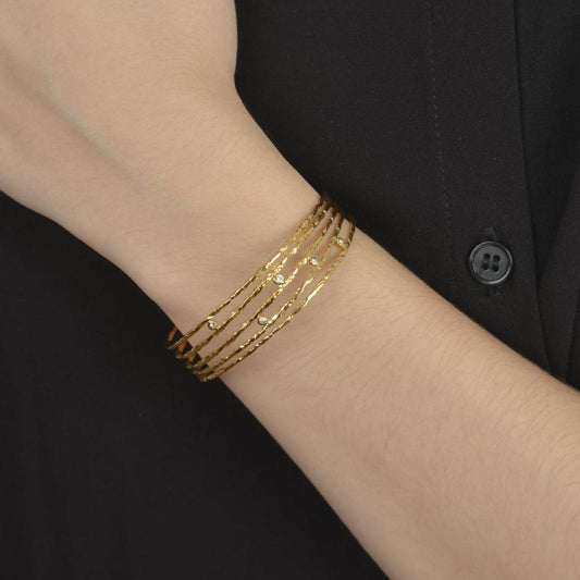 Χρυσό βραχιόλι με πολλαπλές γραμμές και διακοσμητικά ζιργκόν για διαχρονική κομψότητα.