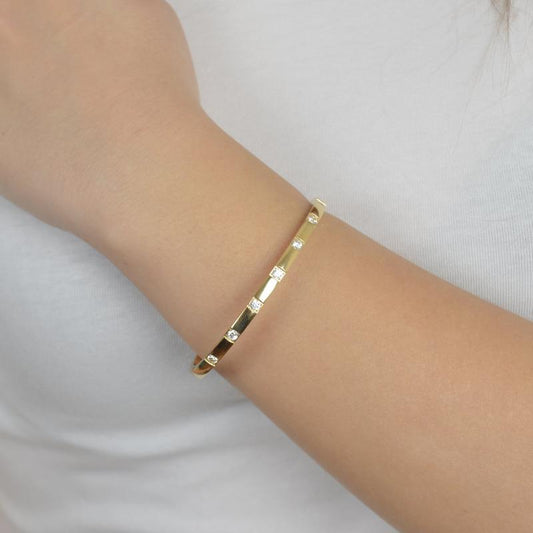Χρυσό βραχιόλι με γεωμετρικά σχέδια και λαμπερές πέτρες για μοντέρνο και κομψό στυλ.