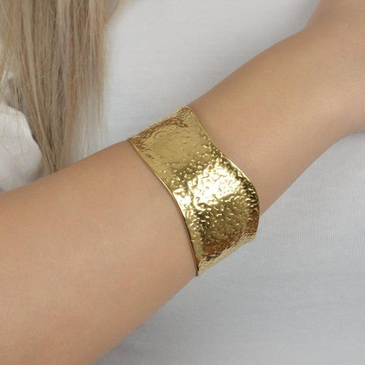 Χρυσό σφυρήλατο βραχιόλι με ακανόνιστες καμπύλες για statement εμφανίσεις.