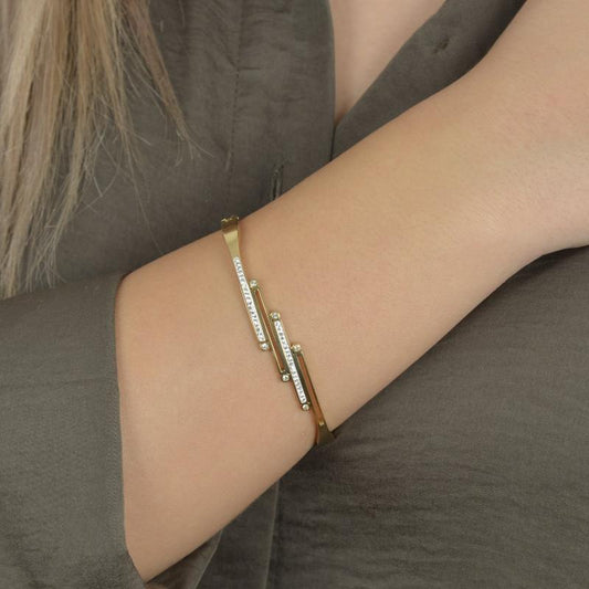 Χρυσό βραχιόλι με κυματιστές γραμμές και λαμπερά ζιργκόν για κομψή εμφάνιση.