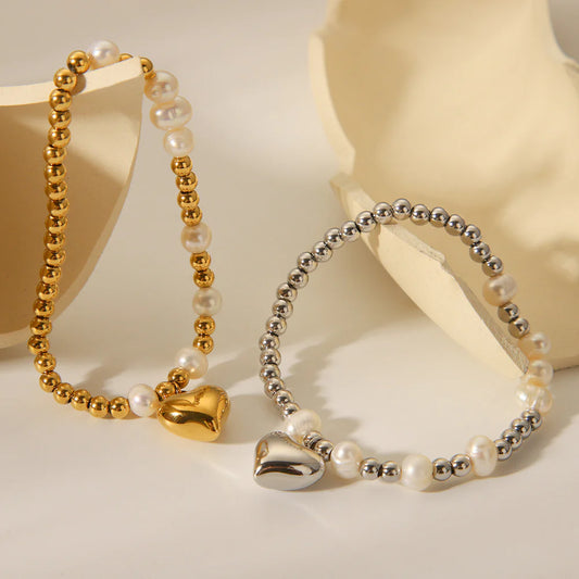 Ασημί βραχιόλι από ανοξείδωτο ατσάλι με πέρλες και charm καρδιά, διάμετρος 5.6cm, βάρος 10.2g.
