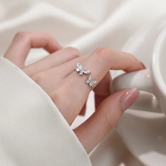 Ανοιχτό ατσάλινο δαχτυλίδι με δύο πεταλούδες από ζιργκόν, φορεμένο σε γυναικείο χέρι.