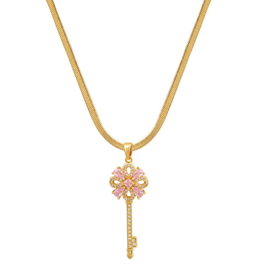 Χρυσό κολιέ με κλειδί στολισμένο με ροζ και λευκά ζιργκόν.